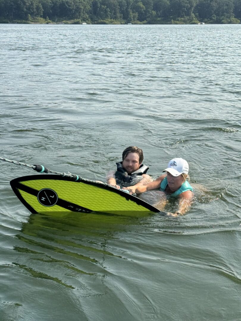 Two people preparing to wakeboard in water.