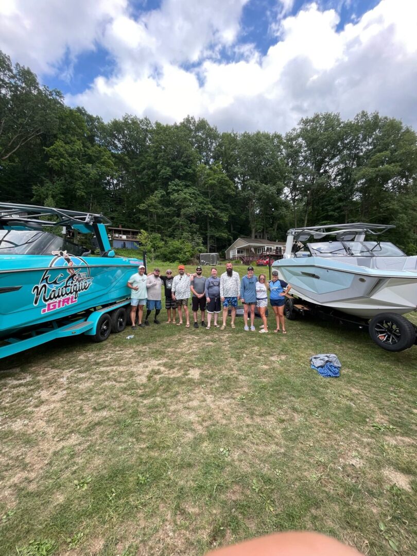 Group posing between two boats outdoors.
