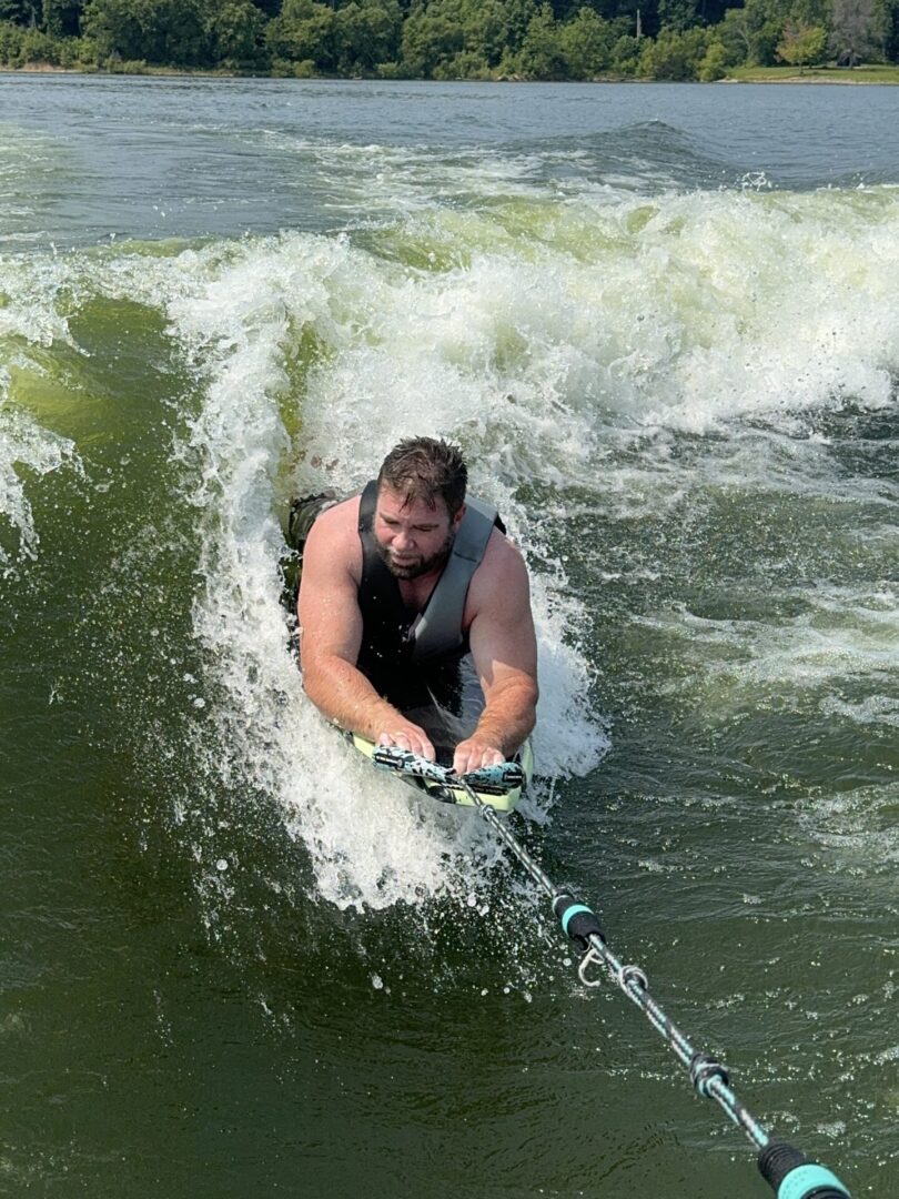 Man kneeboarding on lake with splash.