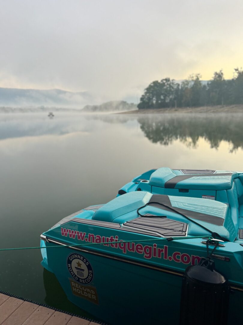Teal boat on calm foggy lake.