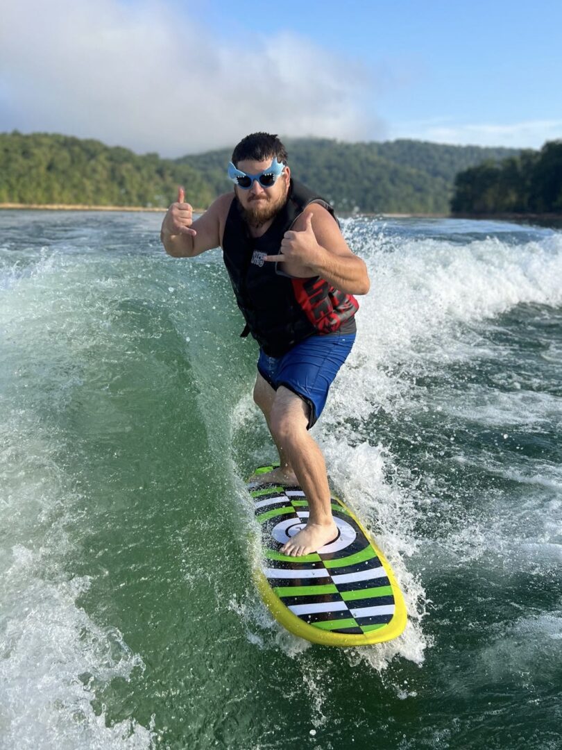 Man surfing on a striped board, smiling.
